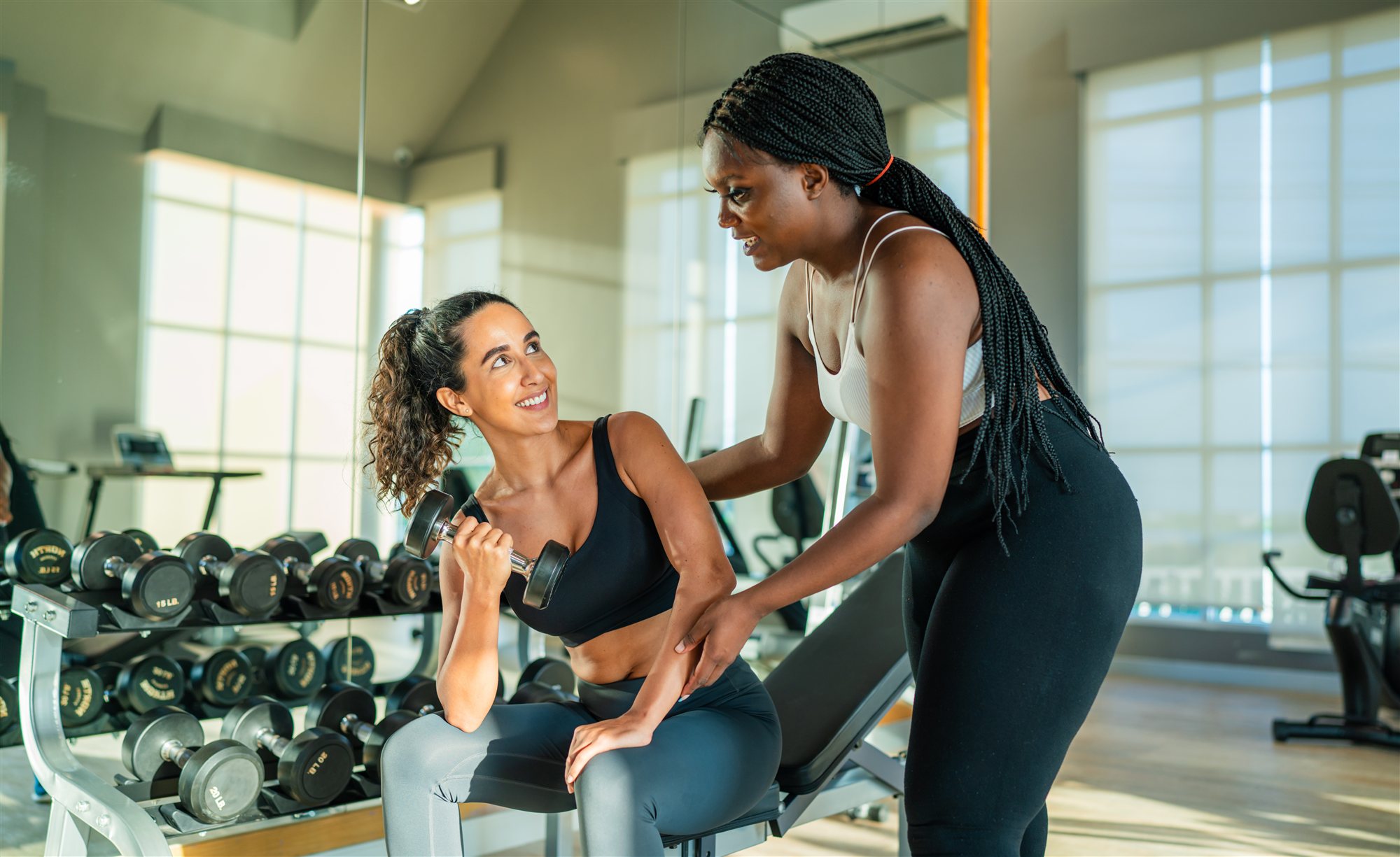 Entrenadora personal asistiendo a una clienta con pesas